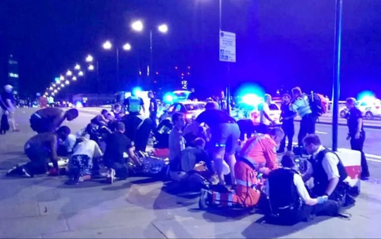 A police officer in uniform standing in front of the London Bridge, with a sombre expression, highlighting the importance of police behaviour and standards in the wake of the London Bridge attack