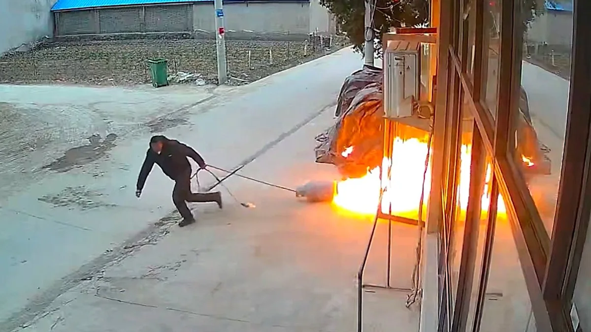 A burning gas cylinder being pulled out of a building by a heroic worker, with flames and smoke in the background, highlighting the importance of gas safety and proper handling of gas cylinders