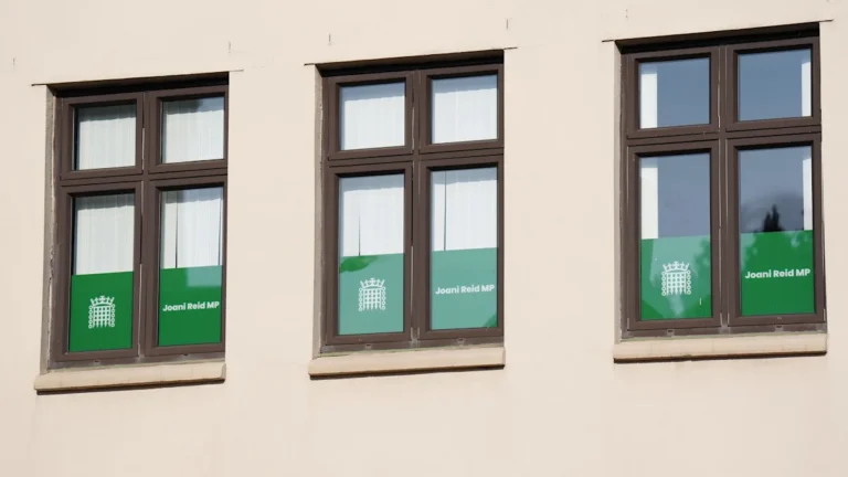 A photograph of the Houses of Parliament in London, with a subtle hint of the Chinese flag in the background, symbolising the alleged China spy links and the potential risks of Chinese espionage in the UK