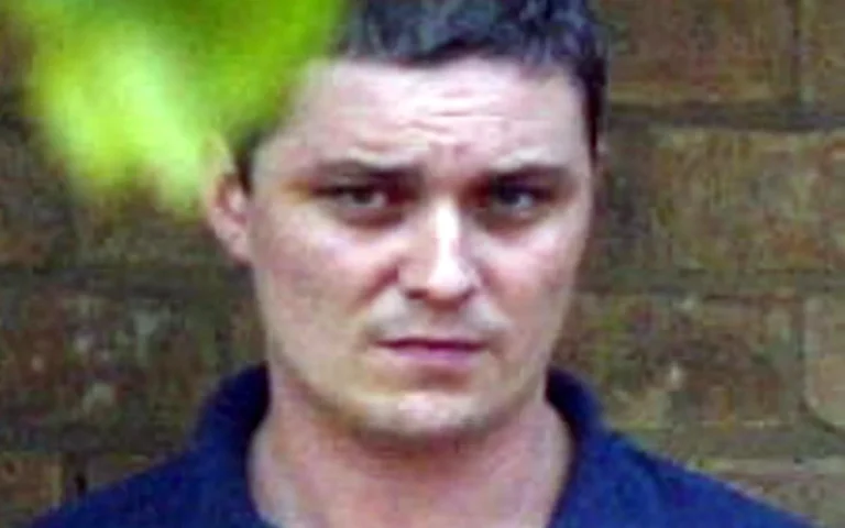 A sombre image of a prison cell, with a hint of darkness and despair, representing the tragic fate of Ian Huntley, a man whose life has been marred by violence and tragedy, and is now on life support after a brutal prison attack