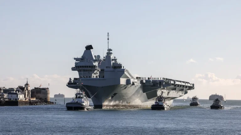 The HMS Prince of Wales aircraft carrier at sea, with several F-35 Lightning II aircraft on its flight deck, showcasing its advanced military capabilities and defence technology