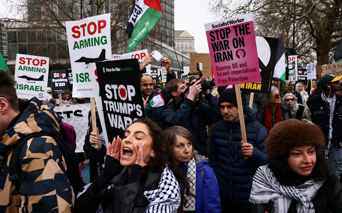Pro-Iranian protesters marching through the streets of London, waving flags and banners in a display of solidarity with the Iranian government, with a strong police presence and a lively atmosphere