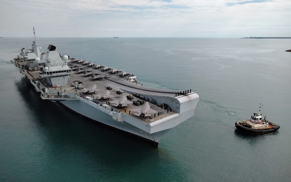 Aircraft carrier at sea, with the UK flag flying high, as the nation considers its defence strategy and potential deployment to the Middle East, a key aspect of its defence plans