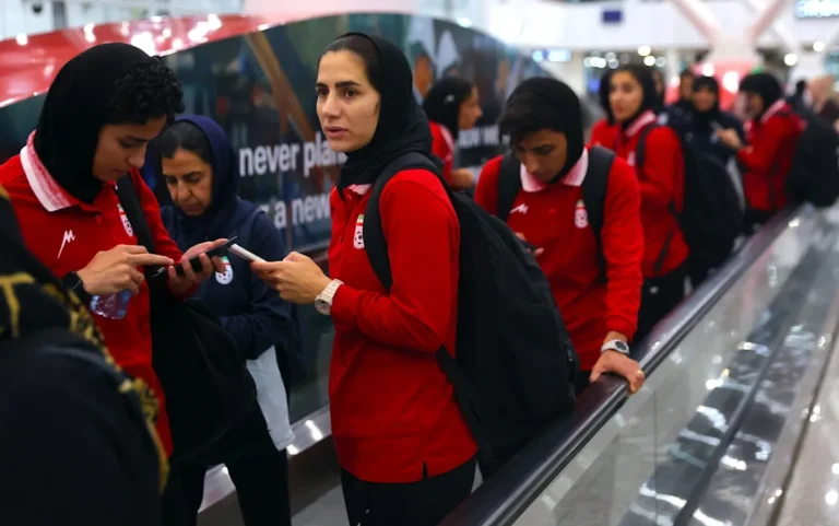 Iranian footballer standing in front of a secret safe house, looking concerned about the squad's security and well-being, with a mix of colour and emotion in the background