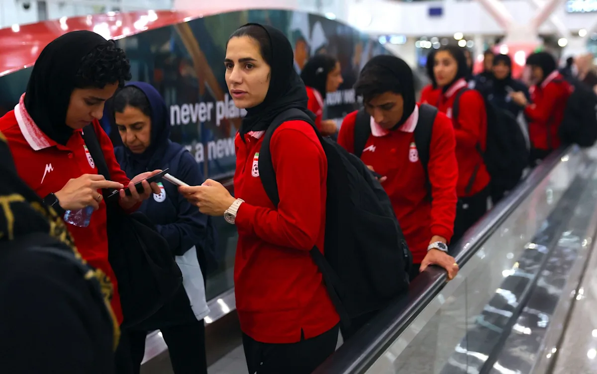 Iranian footballer standing in front of a secret safe house, looking concerned about the squad's security and well-being, with a mix of colour and emotion in the background