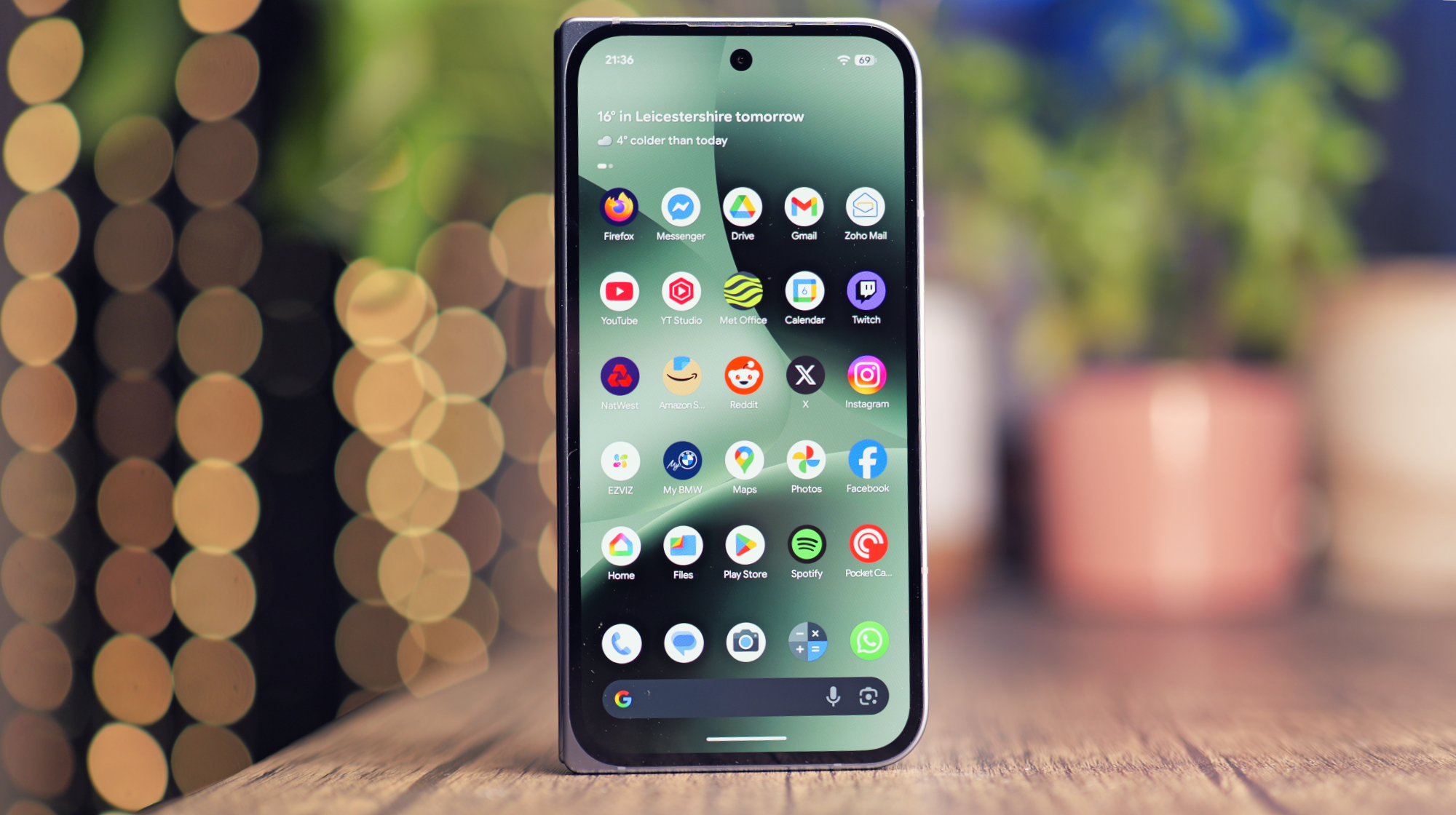 A close-up of a Google Pixel phone's screen, showcasing the new Android features and upgrades, with a blurred background of a person holding the phone, highlighting the UK's mobile landscape and the impact of the Android kernel improvements on the environment.