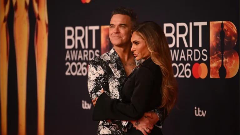 Robbie Williams performing on stage, with a crowd of fans in the background, highlighting his successful music career and the latest development with his management team