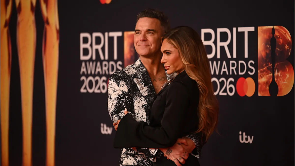Robbie Williams performing on stage, with a crowd of fans in the background, highlighting his successful music career and the latest development with his management team