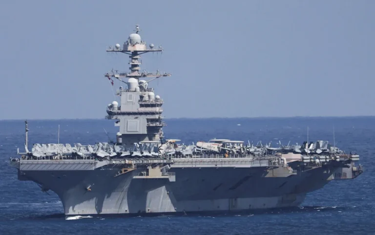 The USS Gerald R Ford warship engulfed in a massive fire, with flames and smoke billowing from the vessel, as firefighters and crew members work to contain the blaze, highlighting the importance of ship safety and maritime security