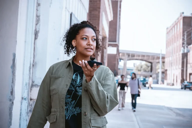 A person holding a phone with a happy expression, surrounded by UK landmarks, with a caption 'Save money on your phone bill with Metro by T-Mobile'