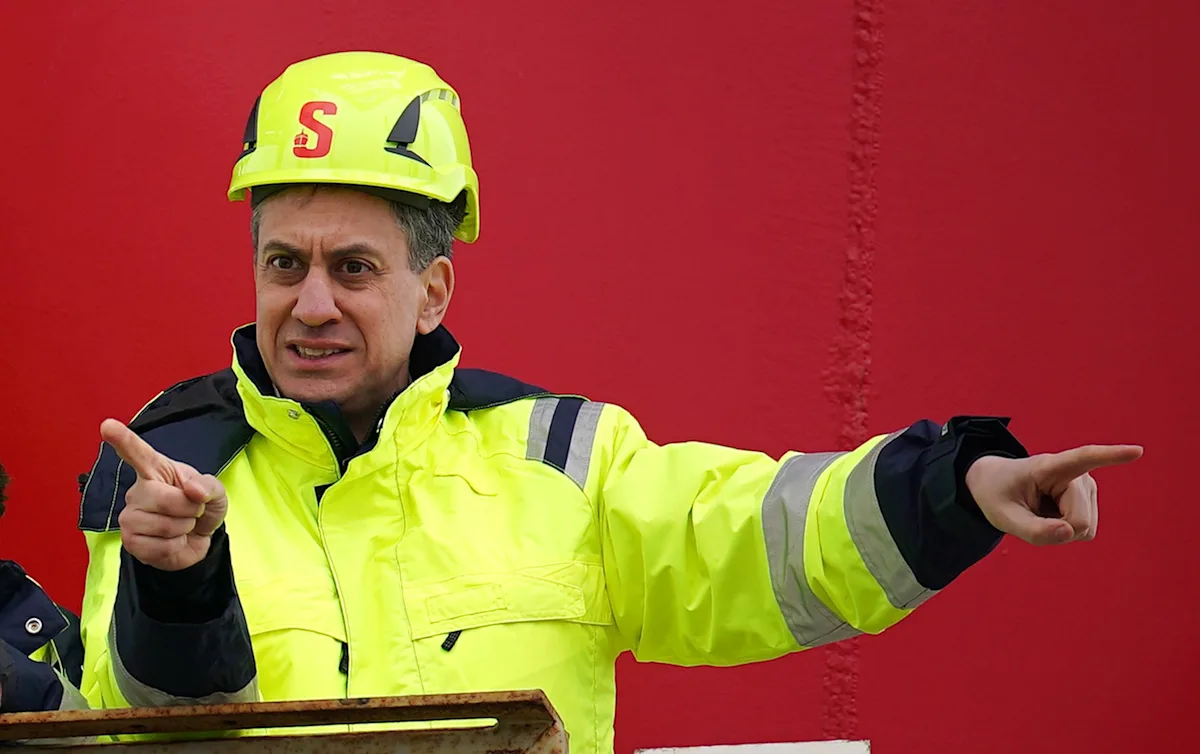 A photograph of a wind farm in the UK, with the caption 'Renewable energy sources, such as wind power, are crucial in reducing carbon emissions and achieving net zero'