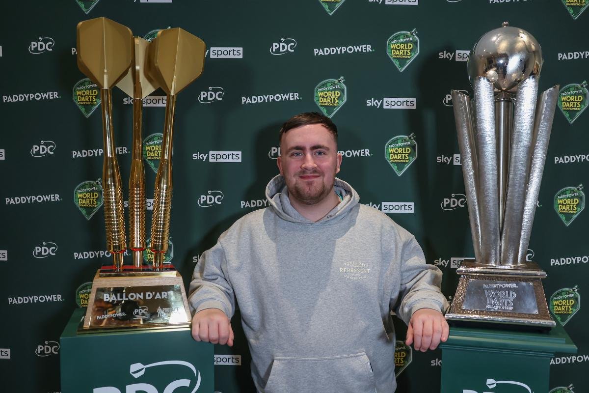 Luke Littler holding darts trophy