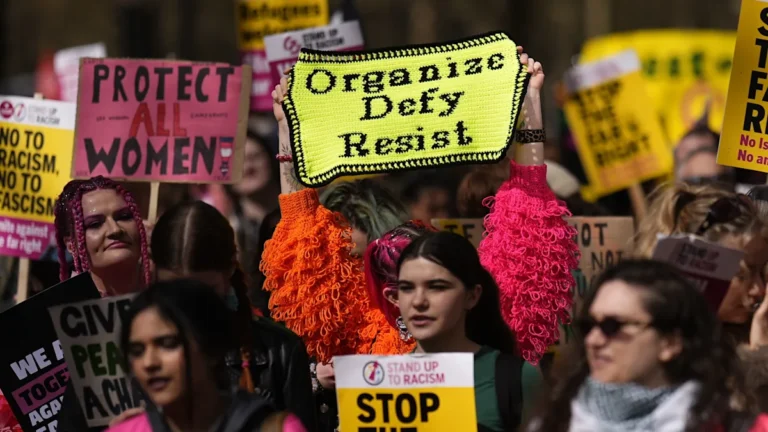 A large crowd of people from diverse backgrounds gathered together, holding signs that promote love, acceptance, and inclusivity, with a clear message of rejecting hate speech and far-right ideology, as rally leaders claim high turnout has intimidated far-right groups