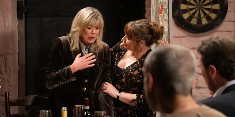 A dramatic scene from Emmerdale, featuring Kim Tate, with a mysterious figure lurking in the background, as the suspects in her poisoning are revealed, and the investigation unfolds