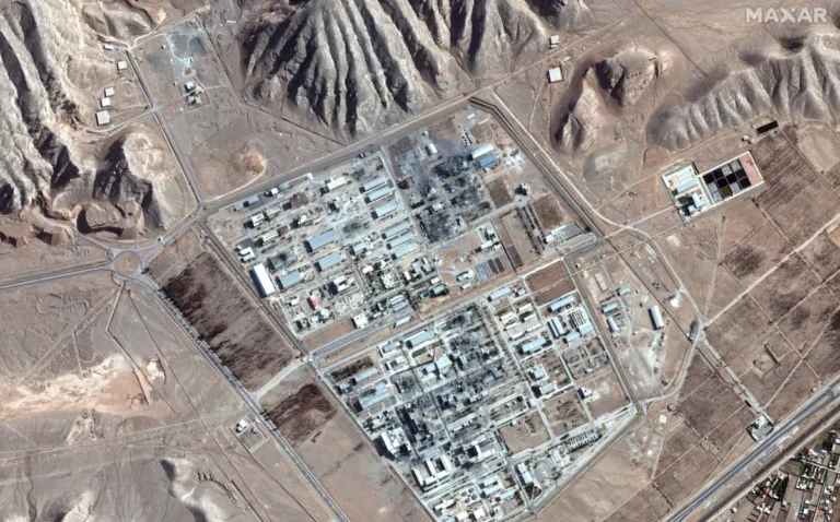 A team of commandos in uniform, equipped with military gear, navigating through a challenging terrain, with a nuclear power plant in the background, the primary keyword is nuclear commando mission