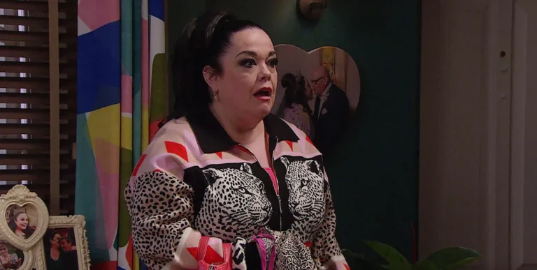 A dramatic scene from Emmerdale featuring Mandy Dingle, with a shocked expression on her face, as the devastating secret surrounding her character begins to unfold, with the village's colourful houses and streets in the background, setting the scene for a suspenseful and emotional storyline