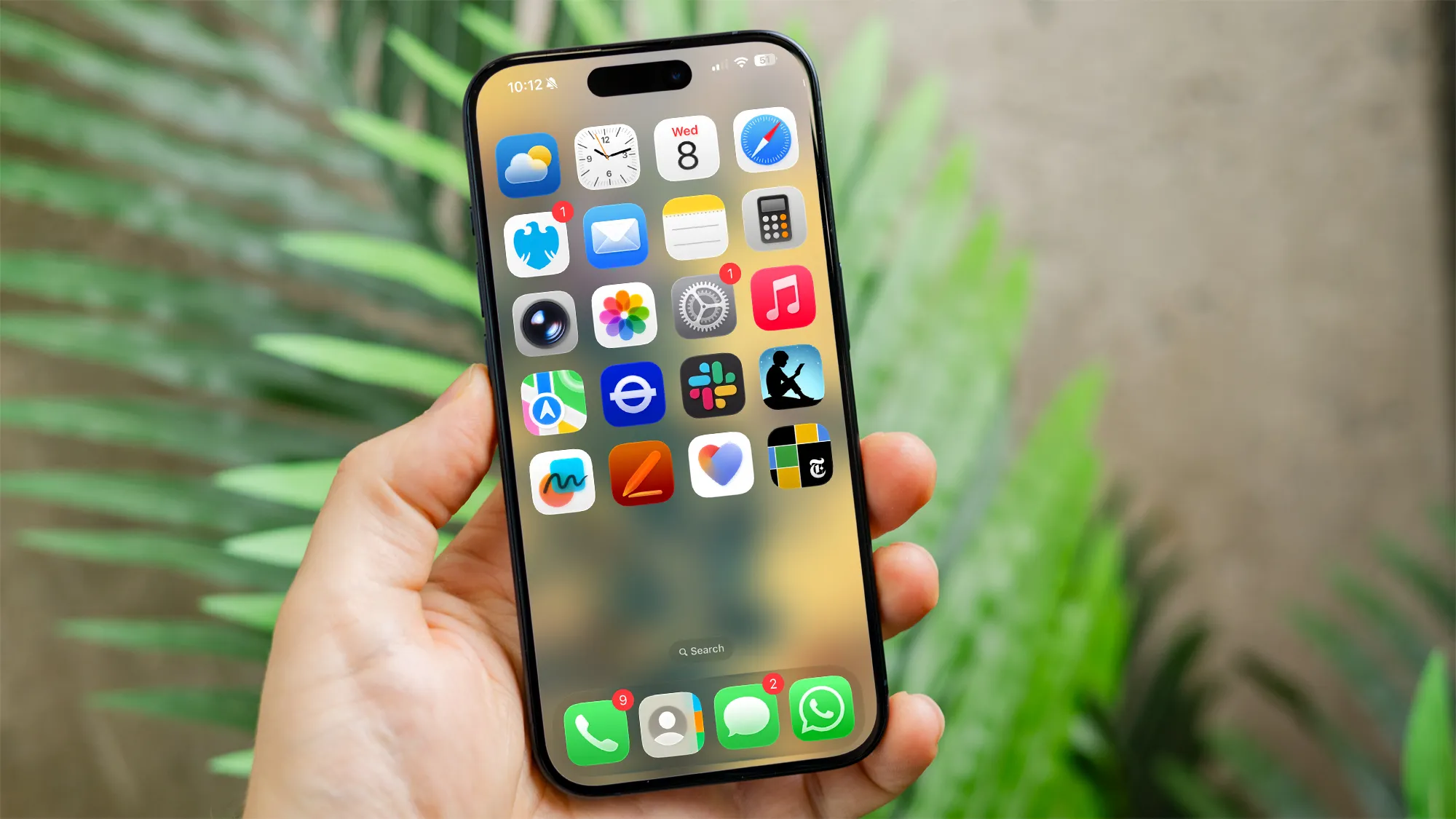 A person playing NYT Games on their smartphone, with a range of puzzles and games on the screen, including Wordle and Pips, with a UK cityscape in the background