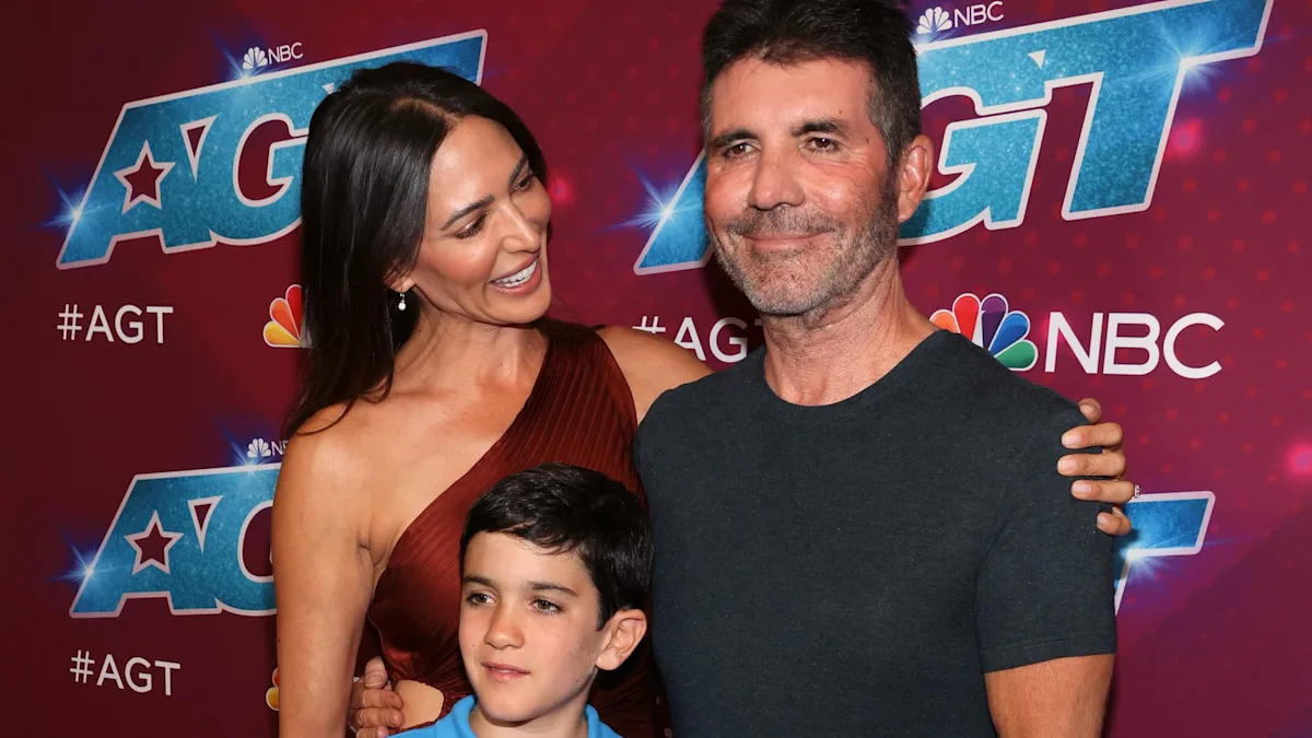 Lauren Silverman and Simon Cowell with son Eric, smiling and happy, with a beautiful colour scheme in the background, as they analyse their family life and behaviour
