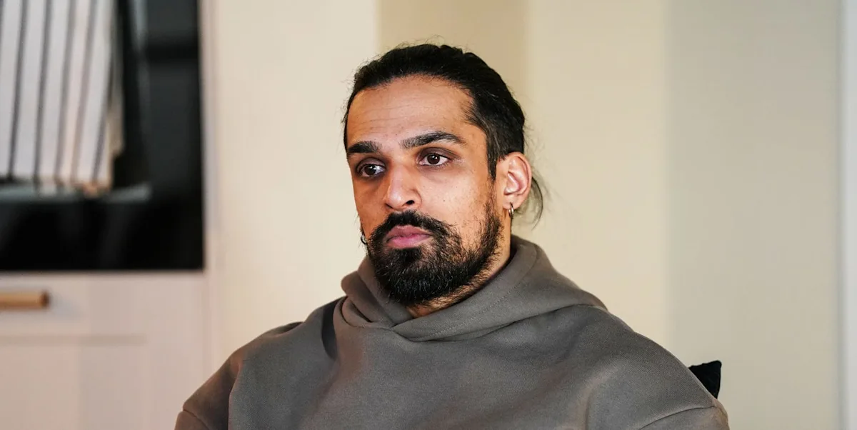 A dramatic scene from EastEnders, featuring the character Ravi, with a surprised expression on his face, set against the colourful backdrop of Albert Square, with a mix of shocked and intrigued residents in the background, highlighting the show's ability to deliver suspense and drama