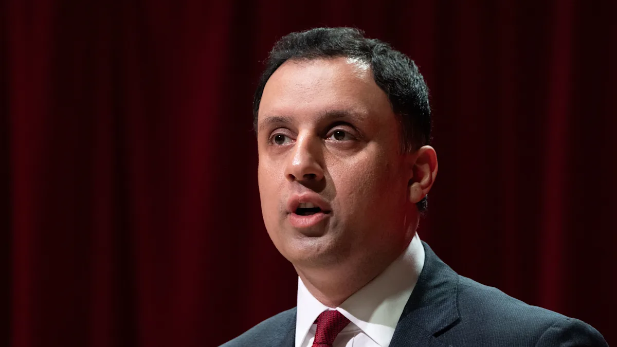 Anas Sarwar speaking at a political rally, with a crowd of supporters in the background, highlighting his enthusiasm and dedication to the Reform party's cause, with a mix of colour and energy in the atmosphere