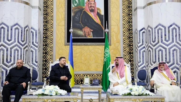 President Zelenskyy shaking hands with Saudi Arabian officials, with a backdrop of Ukrainian and Saudi Arabian flags, symbolising diplomatic efforts to resolve the Ukraine conflict