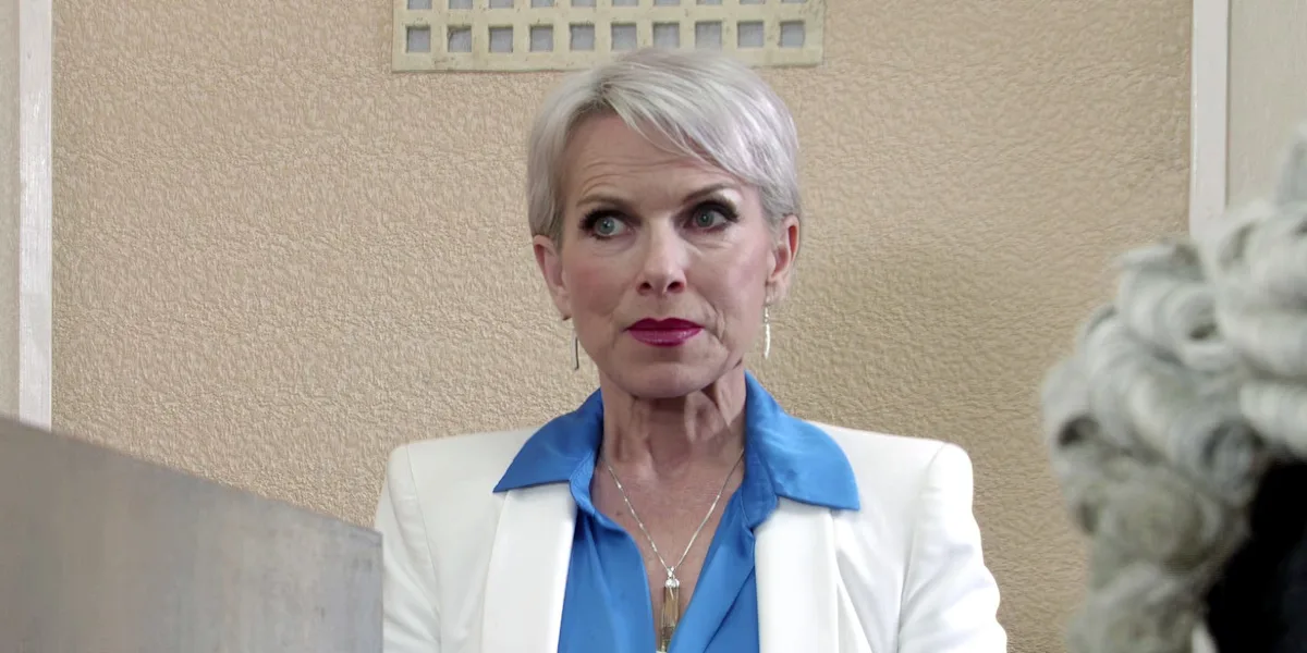 A screenshot of Coronation Street's Debbie, looking concerned and upset, with a blurred background of the soap opera's set, showcasing the show's dramatic and emotional storyline, with a focus on the character's behaviour and relationships