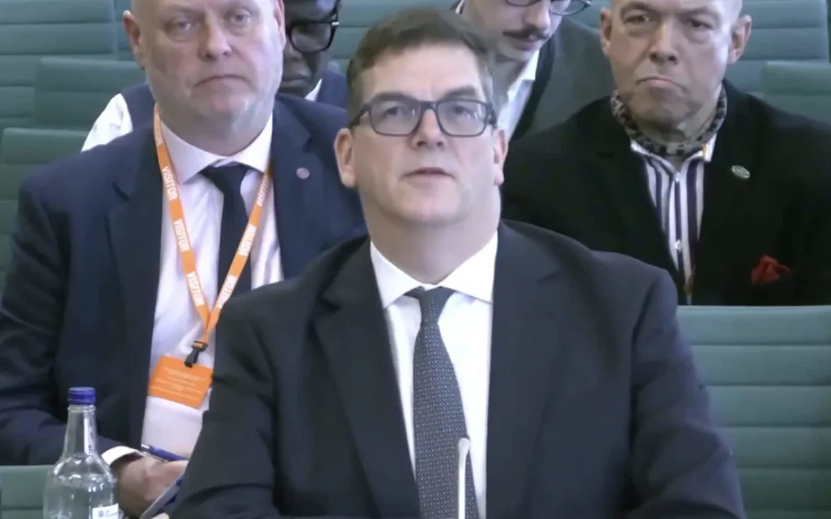 A man wearing a cravat and a suit, blending in with government officials at a high-profile event, with a mix of curiosity and suspicion surrounding his presence, as people try to uncover the mystery of the cravat-wearing gatecrasher