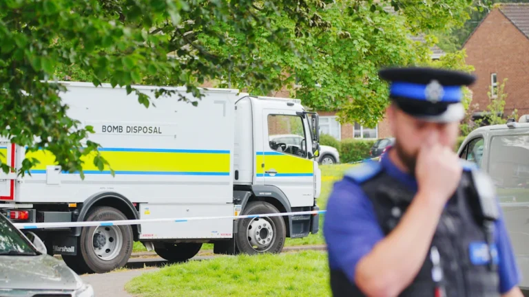 A sombre scene following a fatal explosion, with emergency services attending to those injured and securing the area, highlighting the devastating consequences of such a tragedy, with a focus on the explosion and its impact
