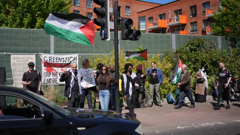 Palestine Action activists protesting outside a factory, with a banner reading 'End the production of military equipment'