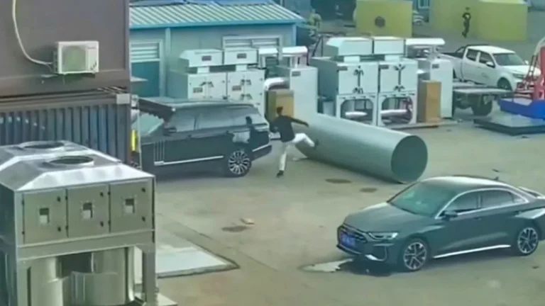 A man pushing a car out of the way of a runaway steel roll, with a look of determination on his face, as people watch in shock and awe, with the steel roll bearing down on the car in the background, with a blurred motion effect to convey the speed and danger of the situation