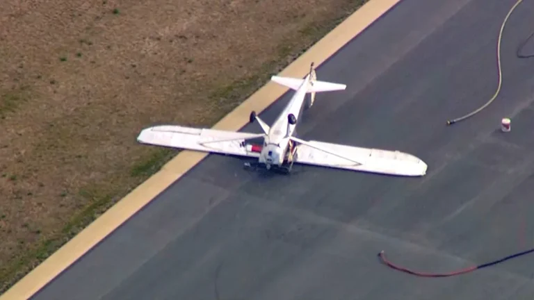 A small plane lies on its roof after flipping over during landing at Cape Cod airport, with emergency responders and debris scattered around the scene, highlighting the importance of the primary keyword phrase 'plane crash'