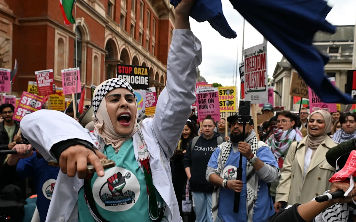 Pro-Palestine protesters holding banners and chanting slogans during a march, with a strong police presence in the background, highlighting the tension and emotion of the event, as they protest in support of the Palestinian cause