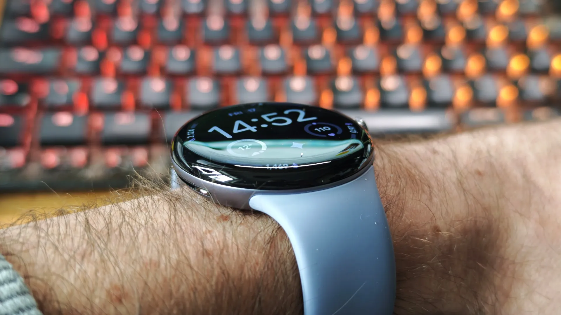 A person wearing a smartwatch with WearOS 7, showcasing its features and improvements, with a cityscape in the background, highlighting the UK context