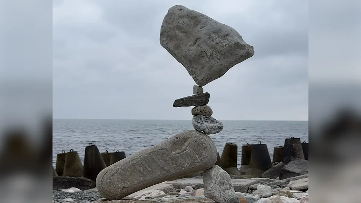 A man carefully balances rocks on top of each other, creating a stunning gravity-defying structure, with the primary keyword rock balancing, in a beautiful outdoor setting with a serene colour palette
