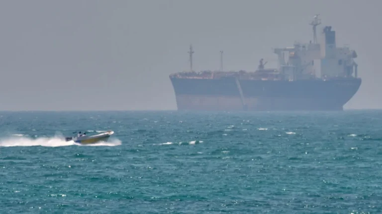 A commercial ship at sea, with the US and Iranian flags in the background, symbolizing the ongoing tensions and blockade, with the primary keyword US Iran blockade