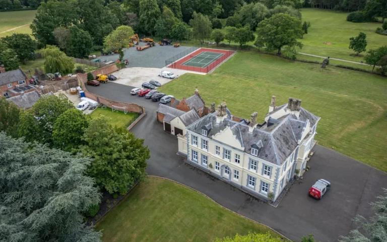 A historic estate with a beautiful landscape and a group of travellers camping in the distance, highlighting the issue of illegal camping and its impact on the environment and conservation
