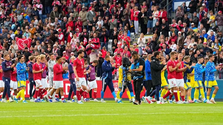 Christian Eriksen collapses on the pitch during a Denmark game, surrounded by concerned teammates and opponents, highlighting the importance of player safety and health in football, with the football community coming together to offer support