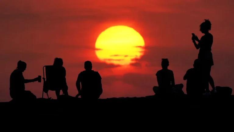 A sunny day in the UK with people enjoying outdoor activities in a park, with a temperature of 30C expected this weekend, perfect weather for a heatwave
