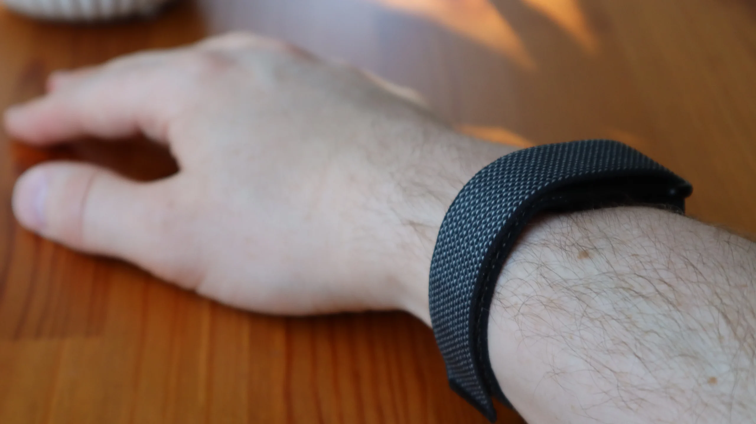 A close-up of a person's wrist wearing a Fitbit Air with an analogue watch attached, showcasing the seamless integration of traditional time-telling and modern fitness tracking, a perfect example of hybrid watches in the UK