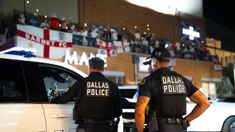 A crowd of England fans cheering and waving flags, with a sea of colour and energy in the background, as they prepare to watch the World Cup opener with a cold beer in hand, analysing every move on the pitch