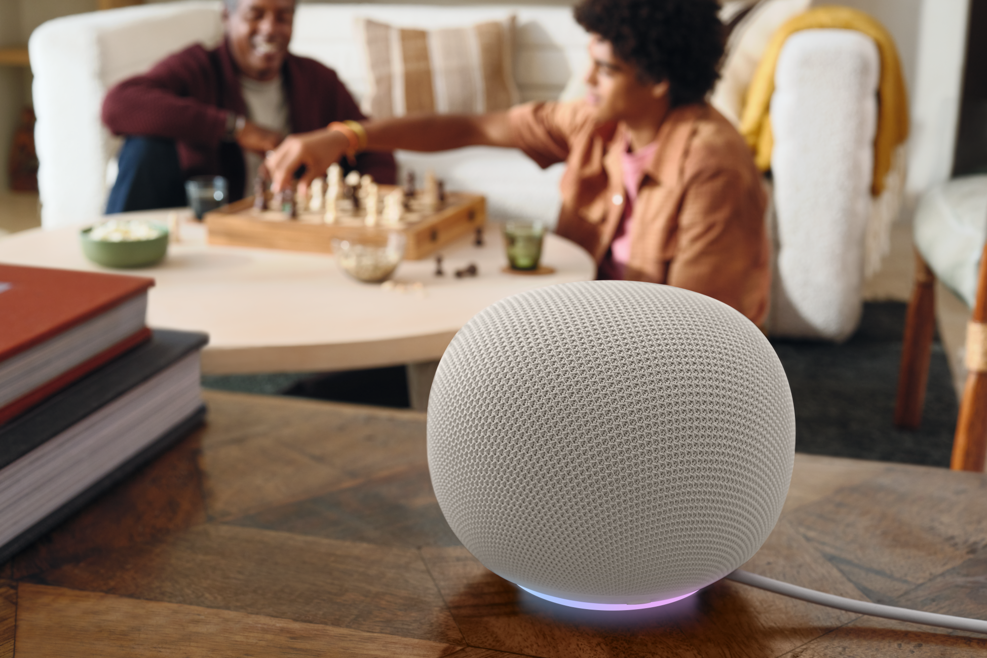 The Google Home Speaker is a sleek and modern smart speaker with a unique orb-shaped design, featuring a ring light around the base and covered in an eco-friendly fabric made from 87% recycled material, available in two colours in the UK.