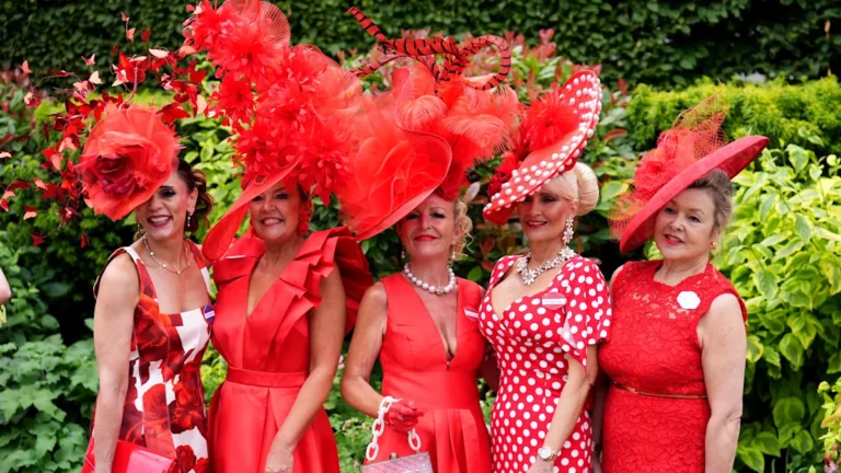 A woman wearing a stunning floral headpiece at Royal Ascot, surrounded by other attendees in elaborate hats, showcasing the event's unique and quirky fashion sense, with a focus on Royal Ascot hats