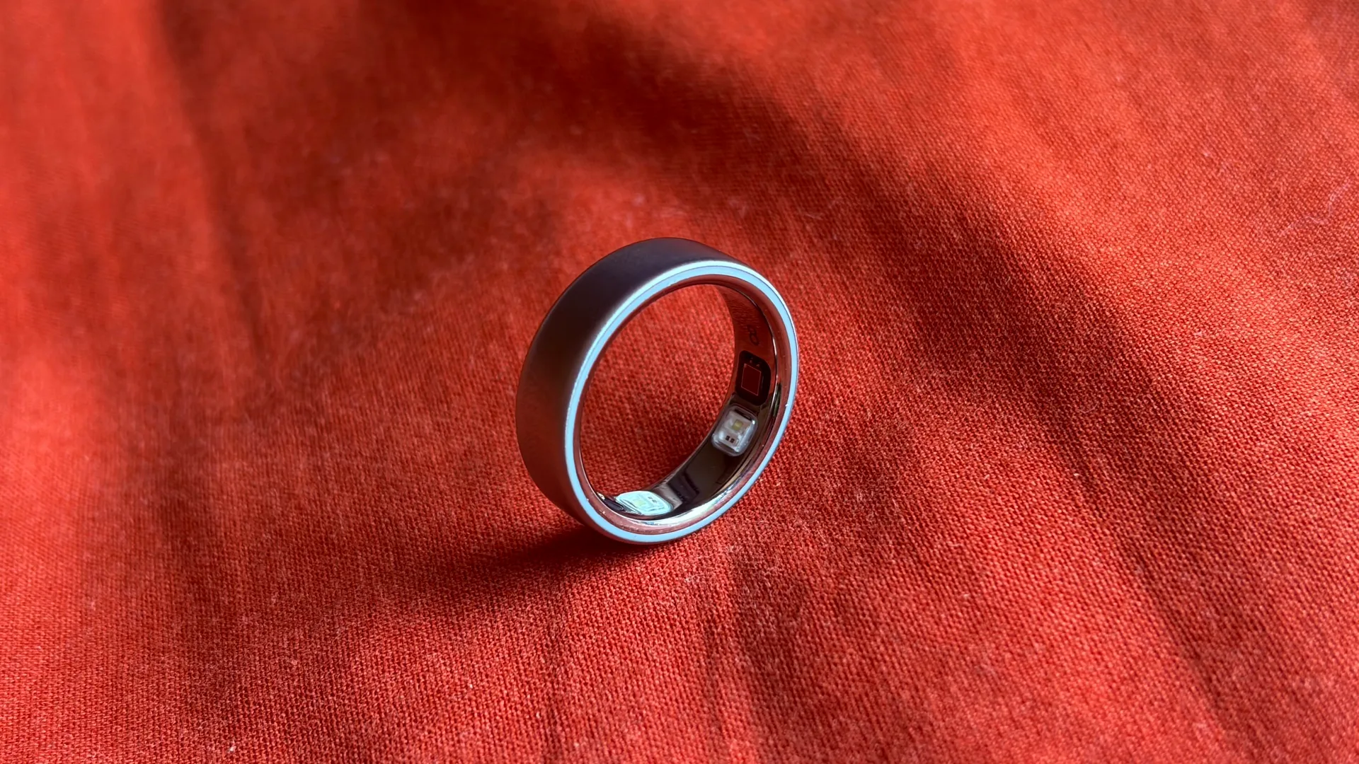 Oura Ring 5 displayed on a fingertip, highlighting its slim titanium design and subtle colour options