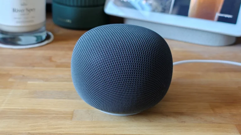 Google Home Speaker in Hazel colour on a kitchen countertop, showing its mesh fabric orb and illuminated ring light.