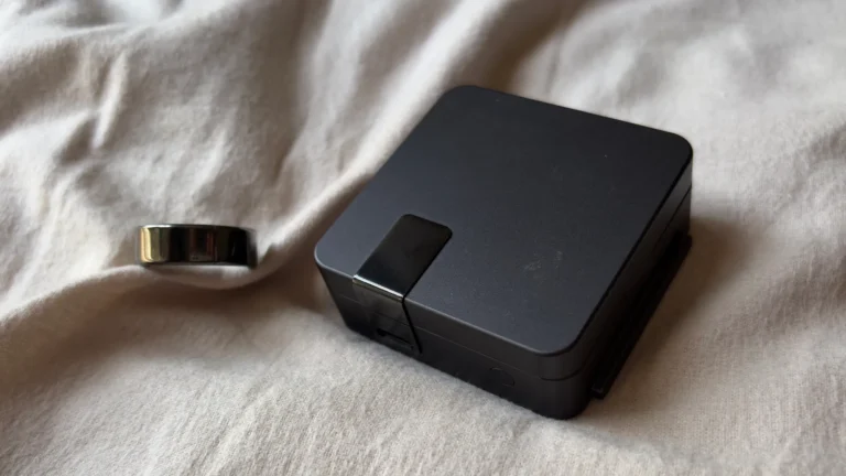 Ultrahuman Ring Pro in titanium finish with charging case displayed on a wooden surface
