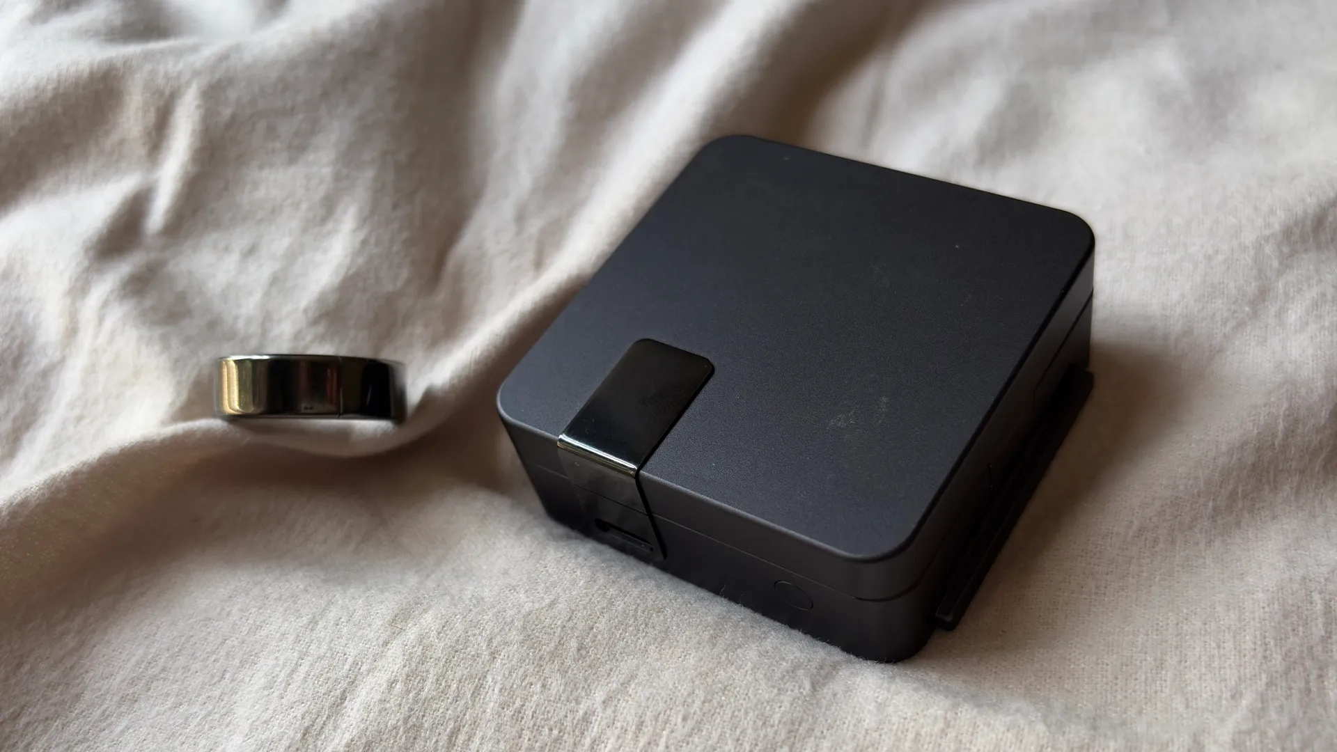 Ultrahuman Ring Pro in titanium finish with charging case displayed on a wooden surface