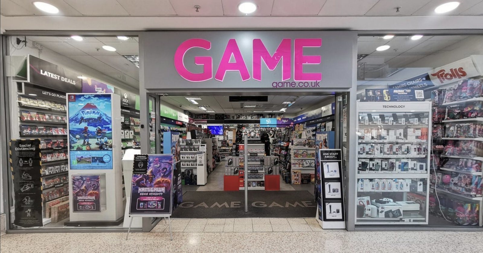 A photo of a GAME store front, with a sign reading 'closing down sale' and customers browsing the shelves. The store is filled with games, consoles, and gaming accessories, and the atmosphere is lively and bustling. The primary keyword, GAME, is prominently displayed on the store front, highlighting the retailer's brand and identity.