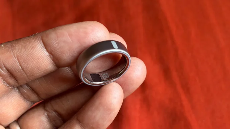 Oura Ring on a person's hand, with a smart light bulb in the background