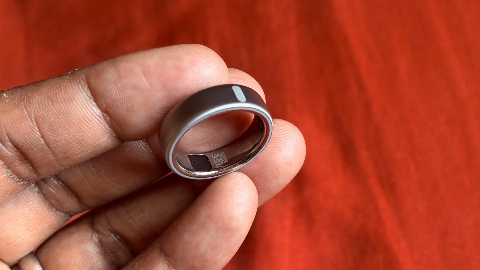 Oura Ring on a person's hand, with a smart light bulb in the background