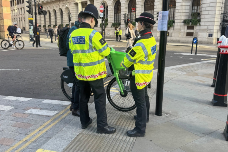 A cyclist riding a bike in London, with a descriptive caption about the dangers of no-handed riding and the importance of road safety, highlighting the primary keyword phrase 'cyclist fined'